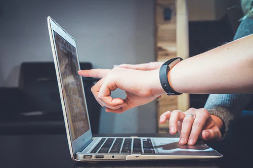 hands pointing at screen of a laptop