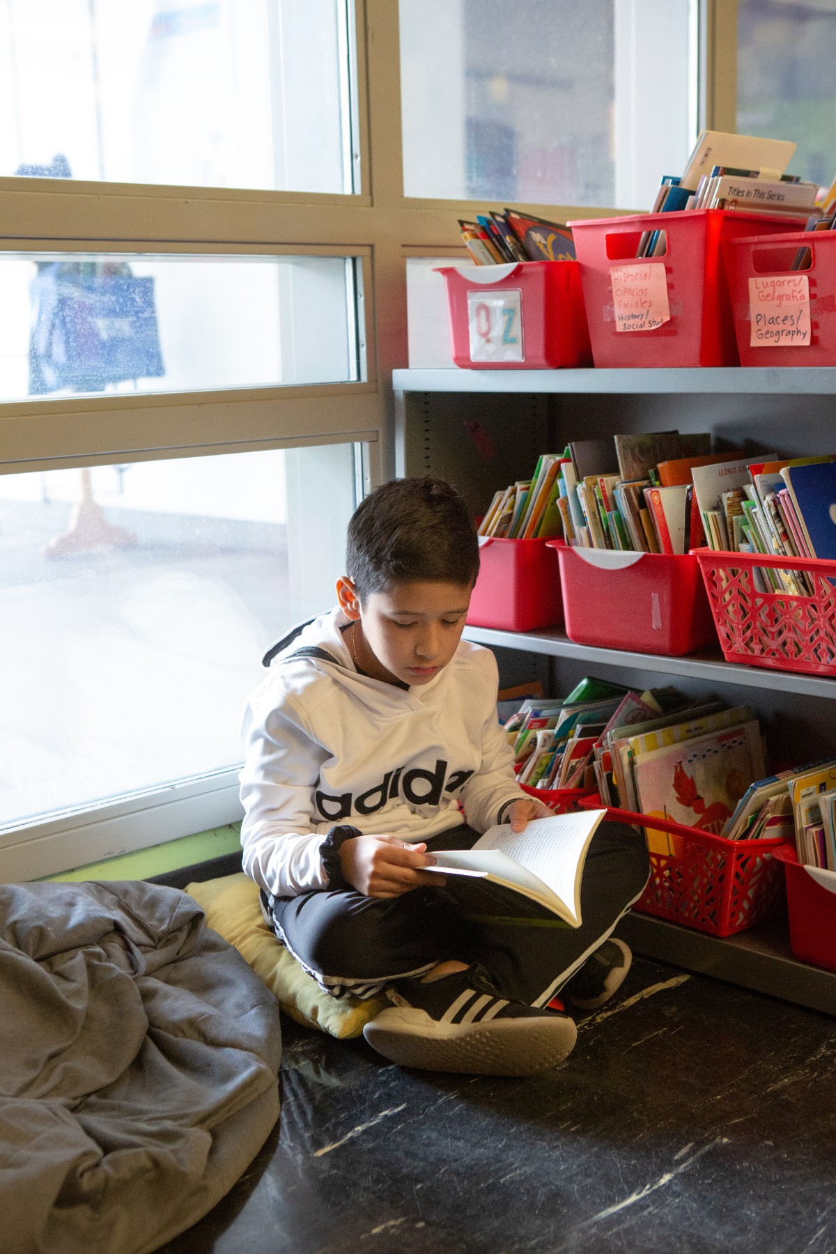 young boy reading a book in a library