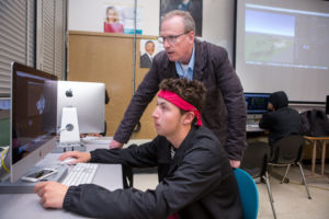 Teacher helps a student at the computer.