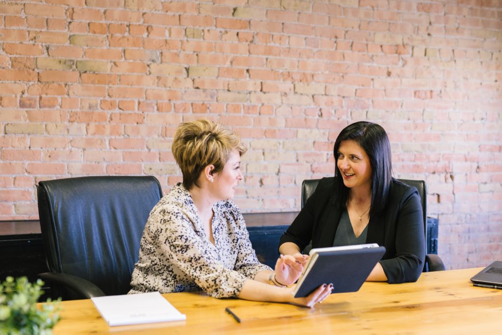 Two women discussing material in a meeting.