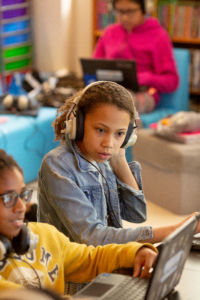 Young female student listen to music in class.